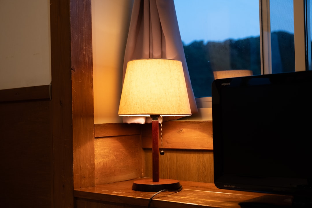 A lit lamp sits on a window ledge.