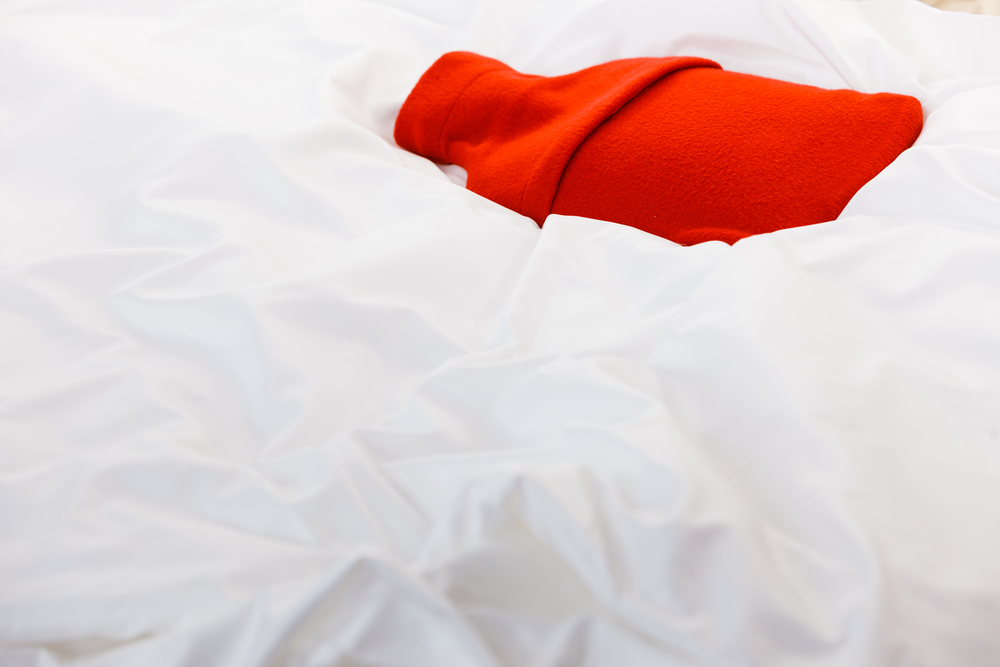 a red hot water bottle in a bed