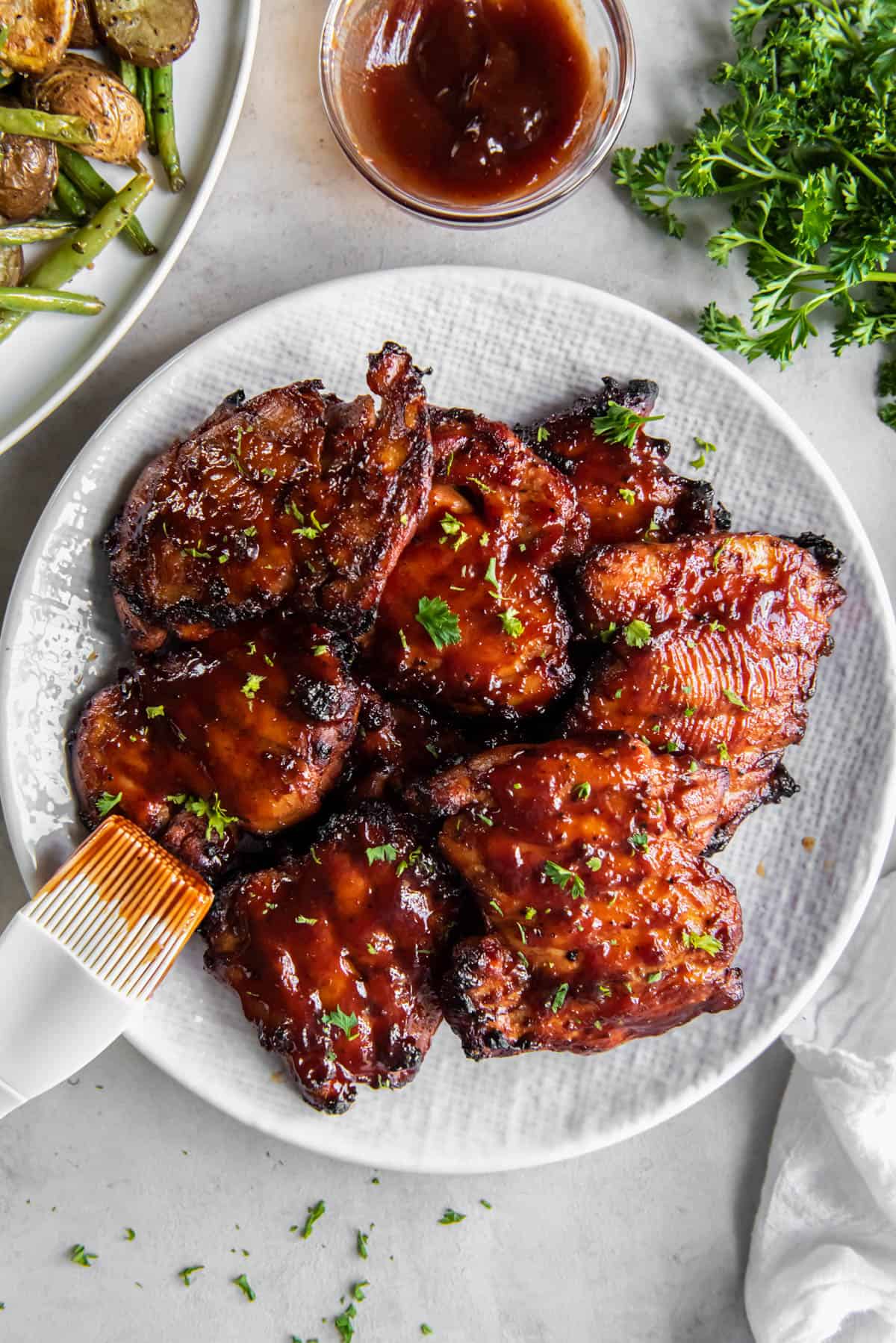 BBQ Boneless Chicken Thighs on a serving plate on a white countertop.