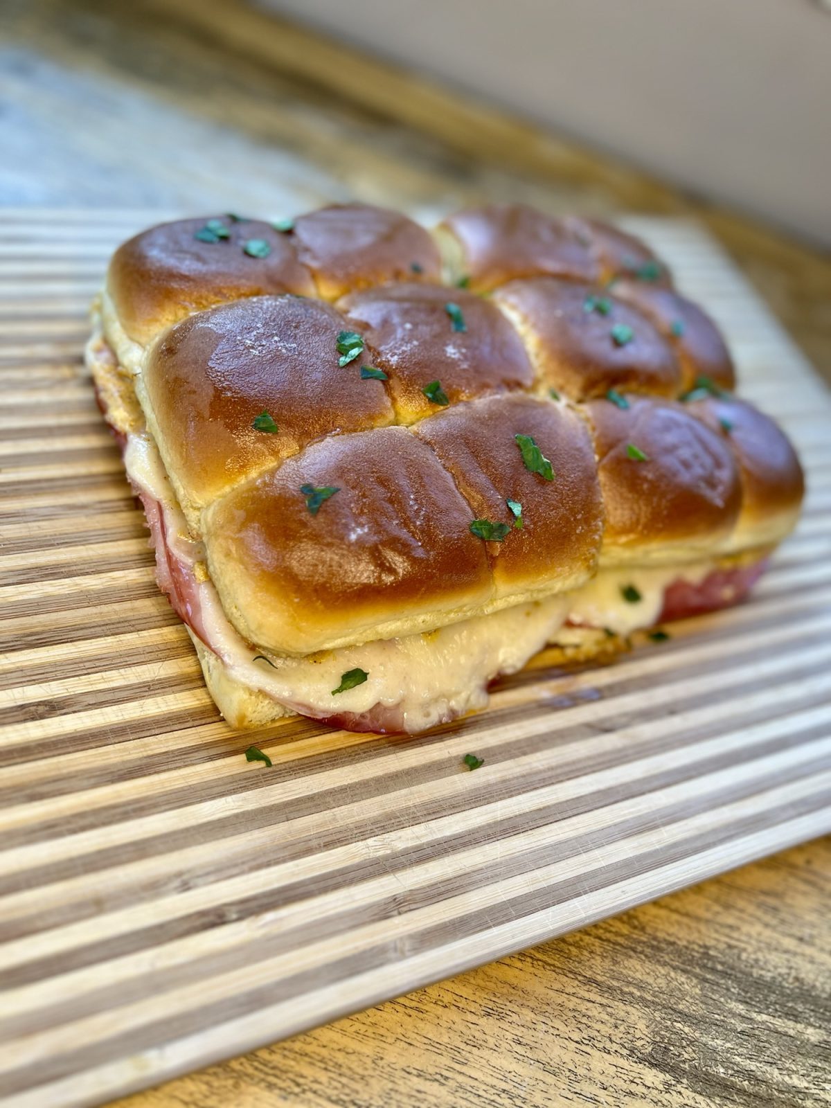 Cubano inspired sliders on a wood cutting board on a wood table