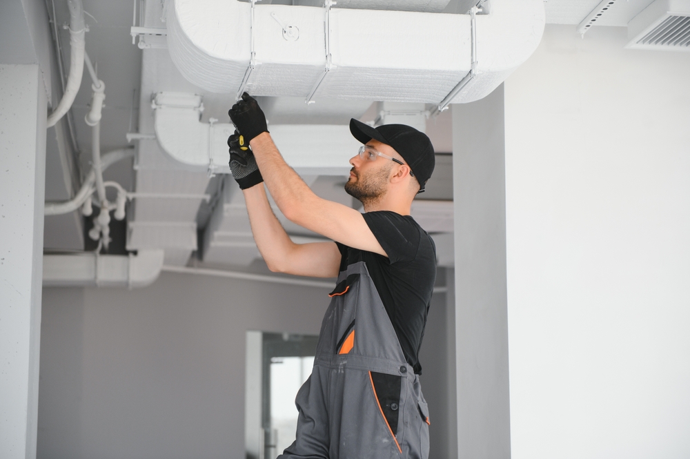 HVAC worker mending duct pipes