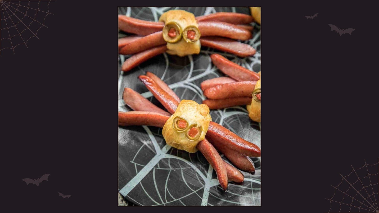 Baked spider-shaped hot dogs with crescent pastry bodies and olive eyes