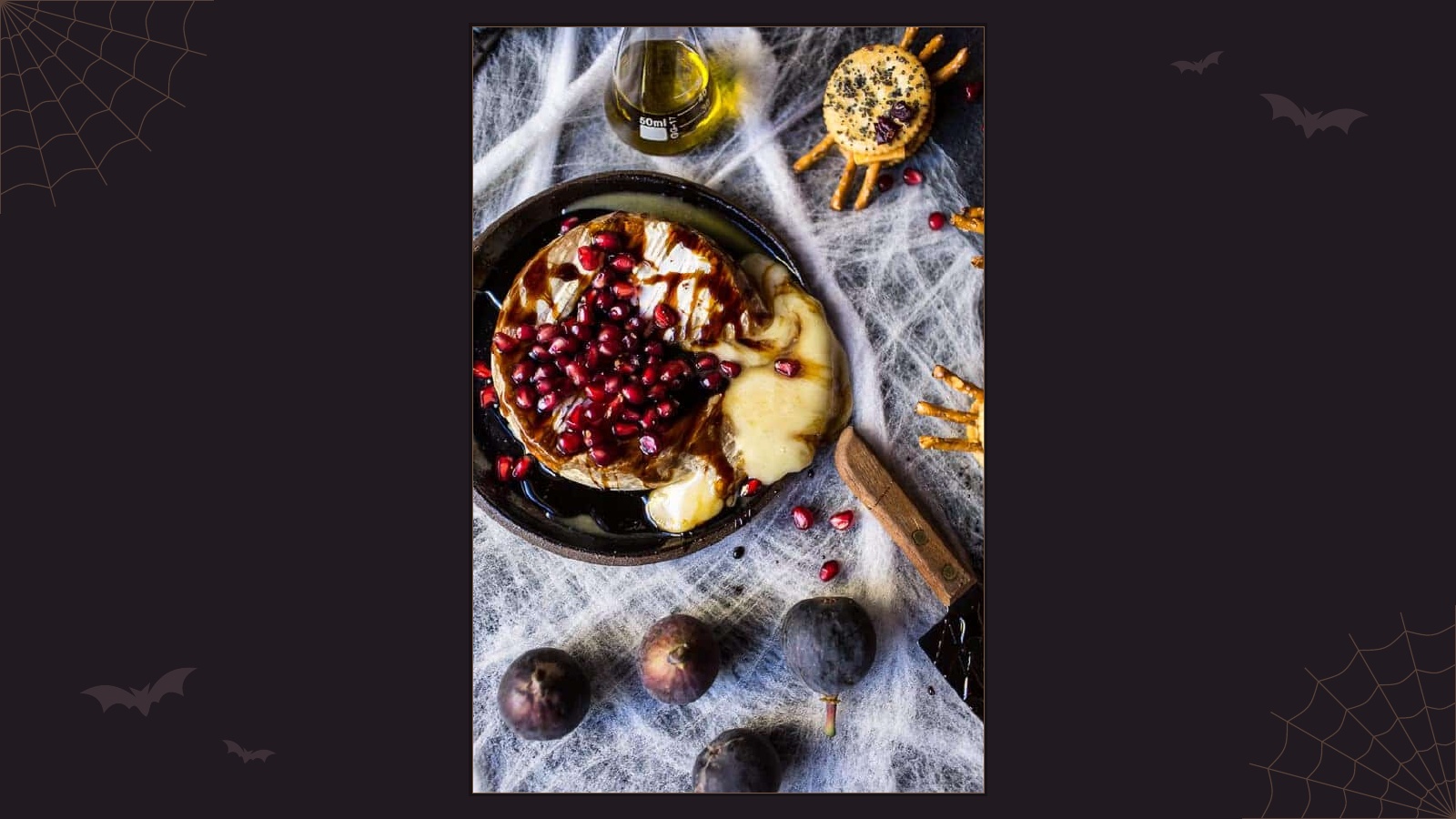 Halloween-inspired cheese board featuring warm baked brie, pomegranate seeds, fruit and crackers