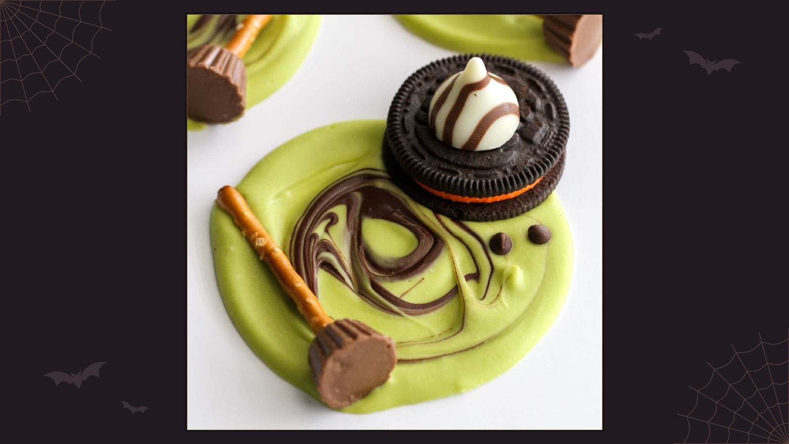 Green melted witch chocolate bark decorated with an Oreo hat, chocolate candies and a pretzel broom