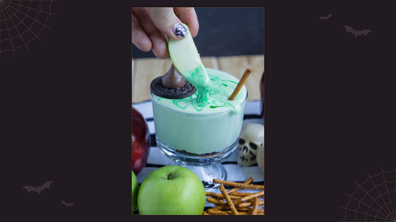 Green melted witch fruit dip with an apple slice, cookie hat and pretzel broomstick