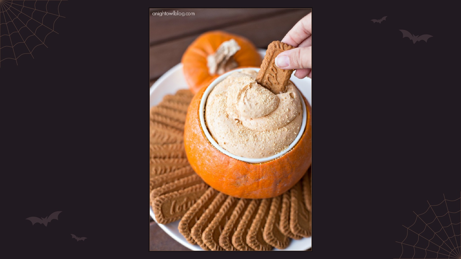 Creamy pumpkin pie cheesecake dip served in a small hollowed pumpkin with cookies