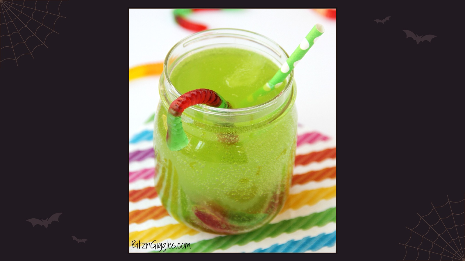 Green fizzy punch in a glass jar with colorful gummy worms emerging from the drink