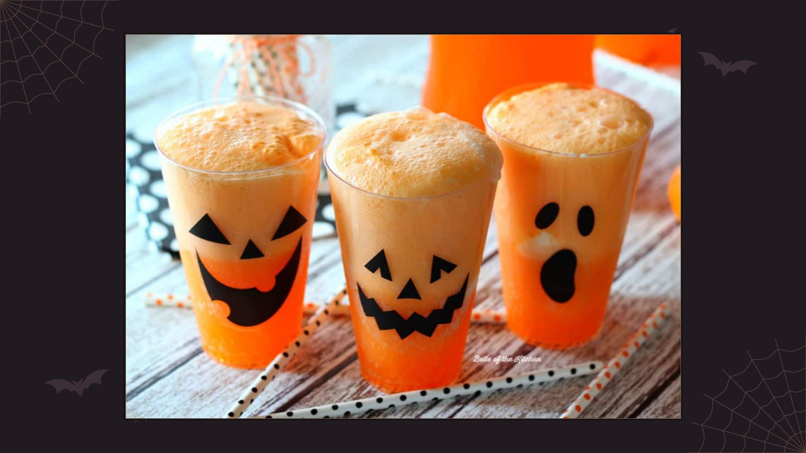 Three orange soda and vanilla ice cream floats in cups decorated with jack-o'-lantern faces