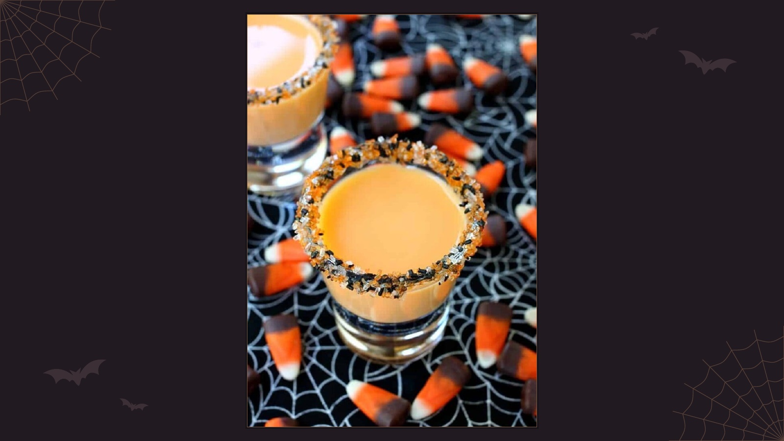 Creamy orange pumpkin pie shots in glasses rimmed with black and orange sugar