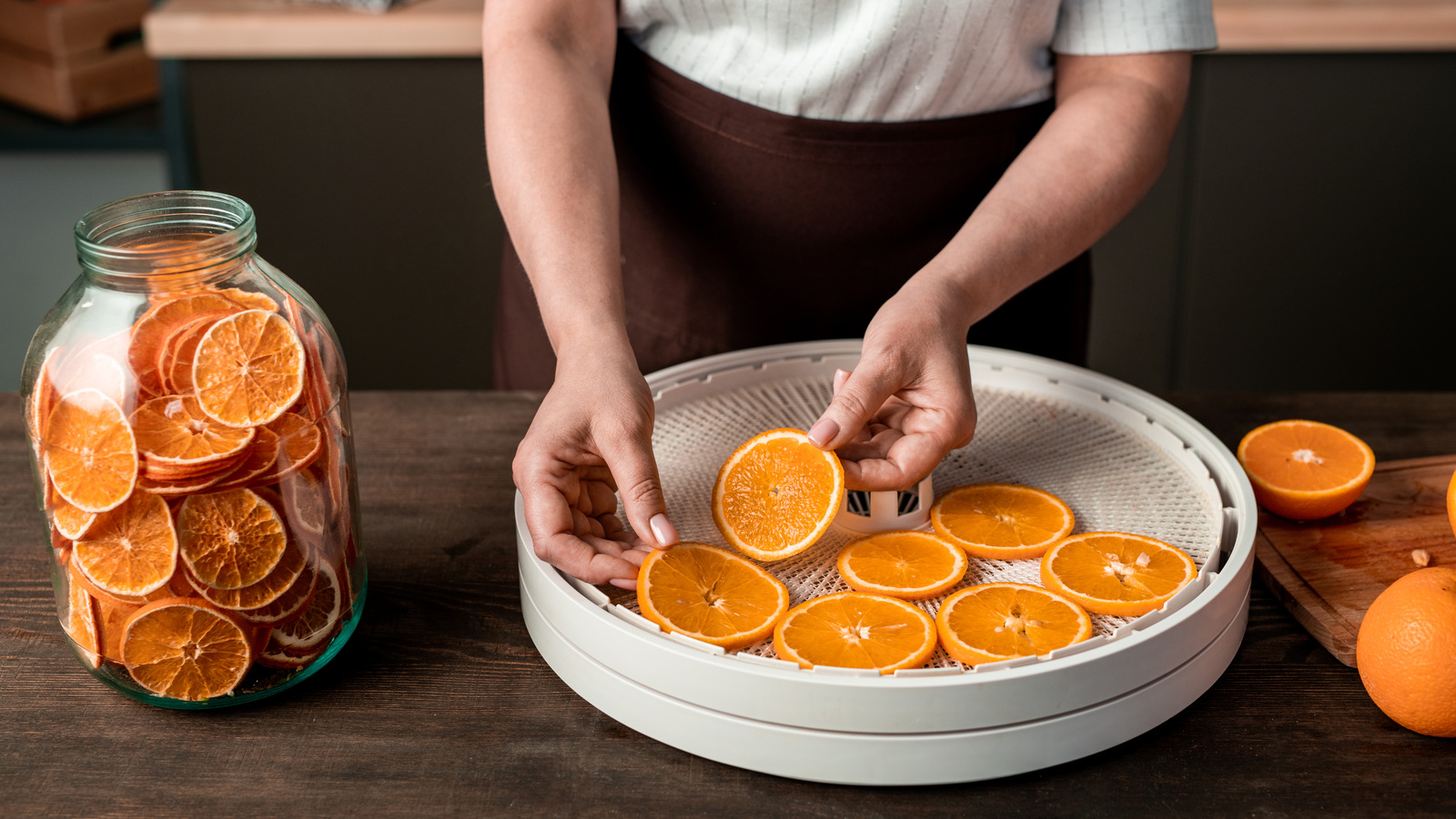 Person placing fresh orange rounds in a single layer on a dehydrator tray