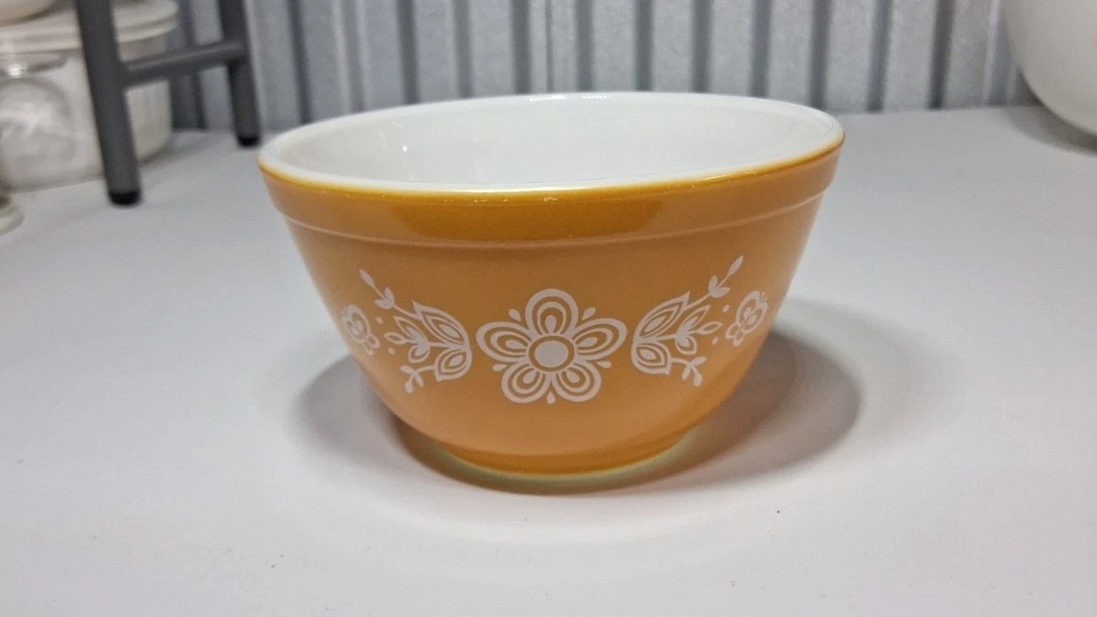 Butterscotch-gold Pyrex bowl with the original large central white flower and symmetrical leaves and butterflies