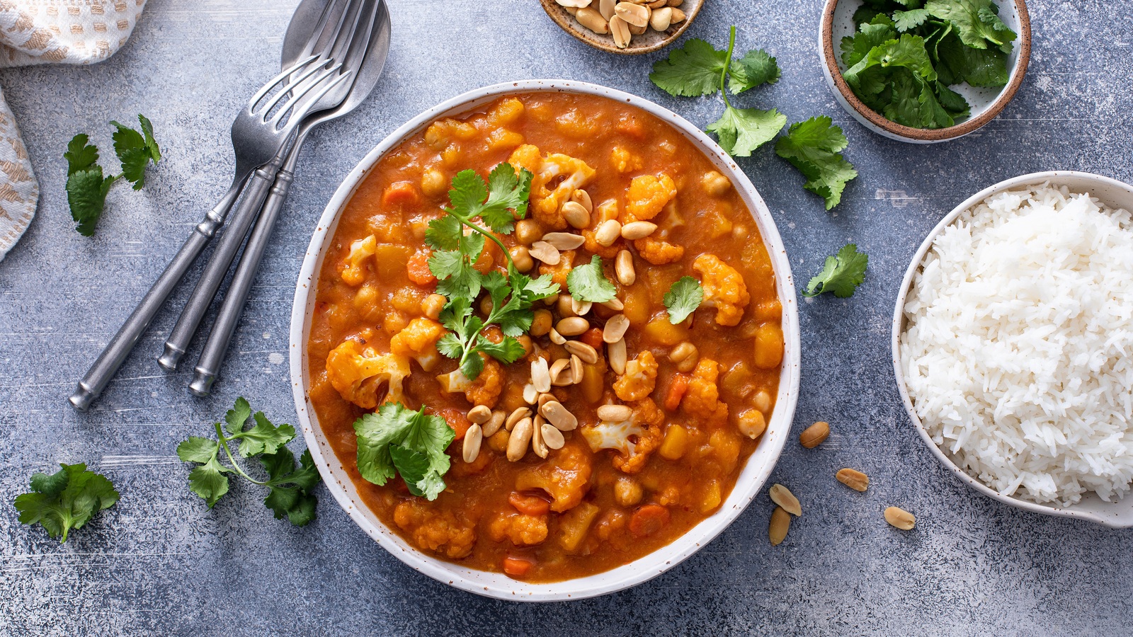 Butternut squash and chickpea curry topped with peanuts, served beside rice