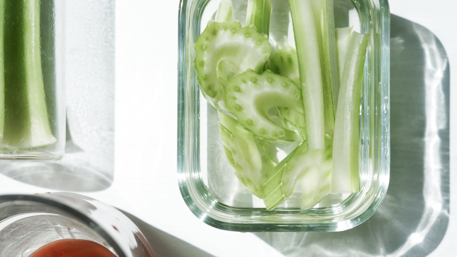 Cut celery pieces submerged in water in a clear glass kitchen container