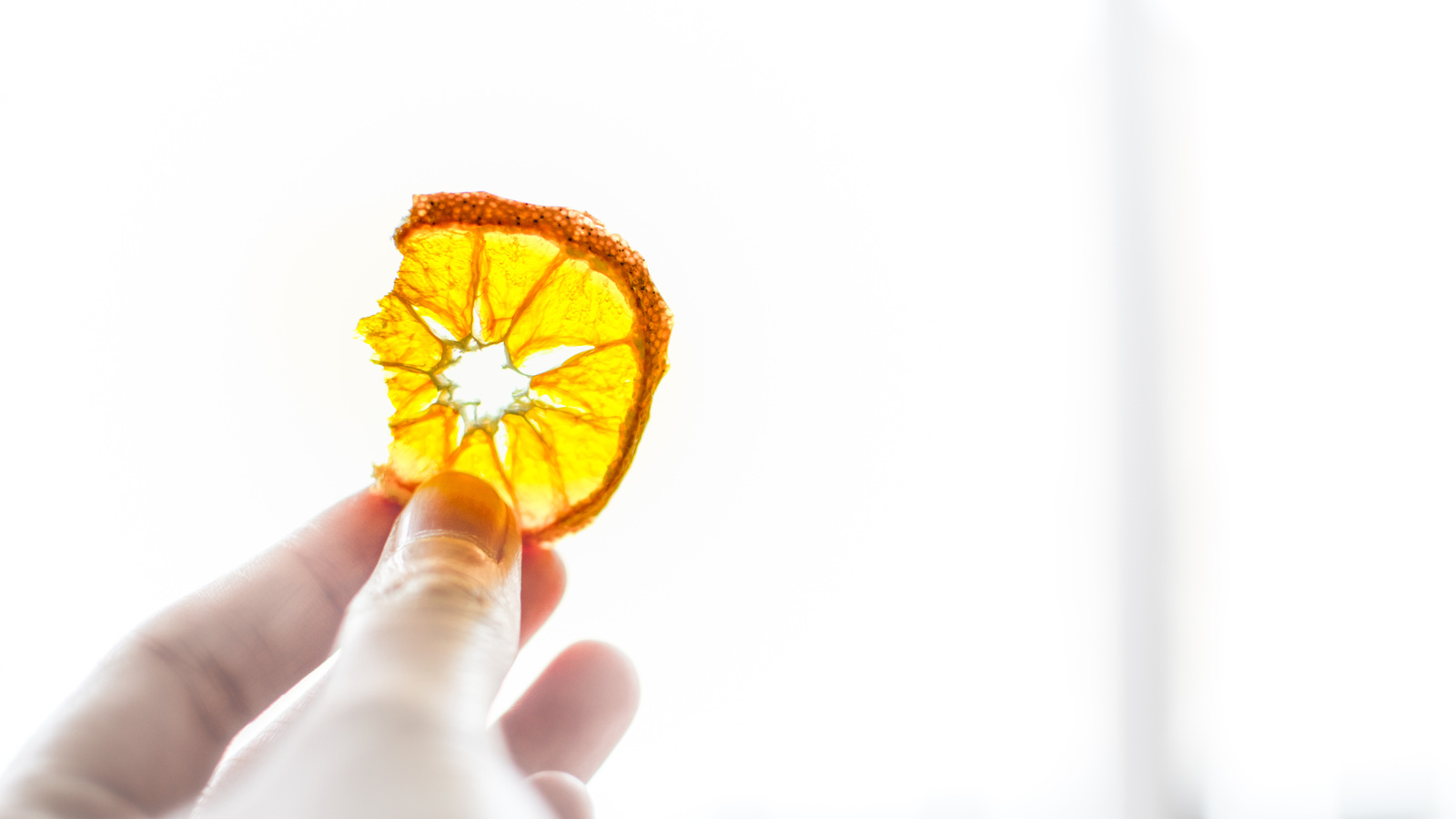 Hand holding a broken dried orange slice against the light