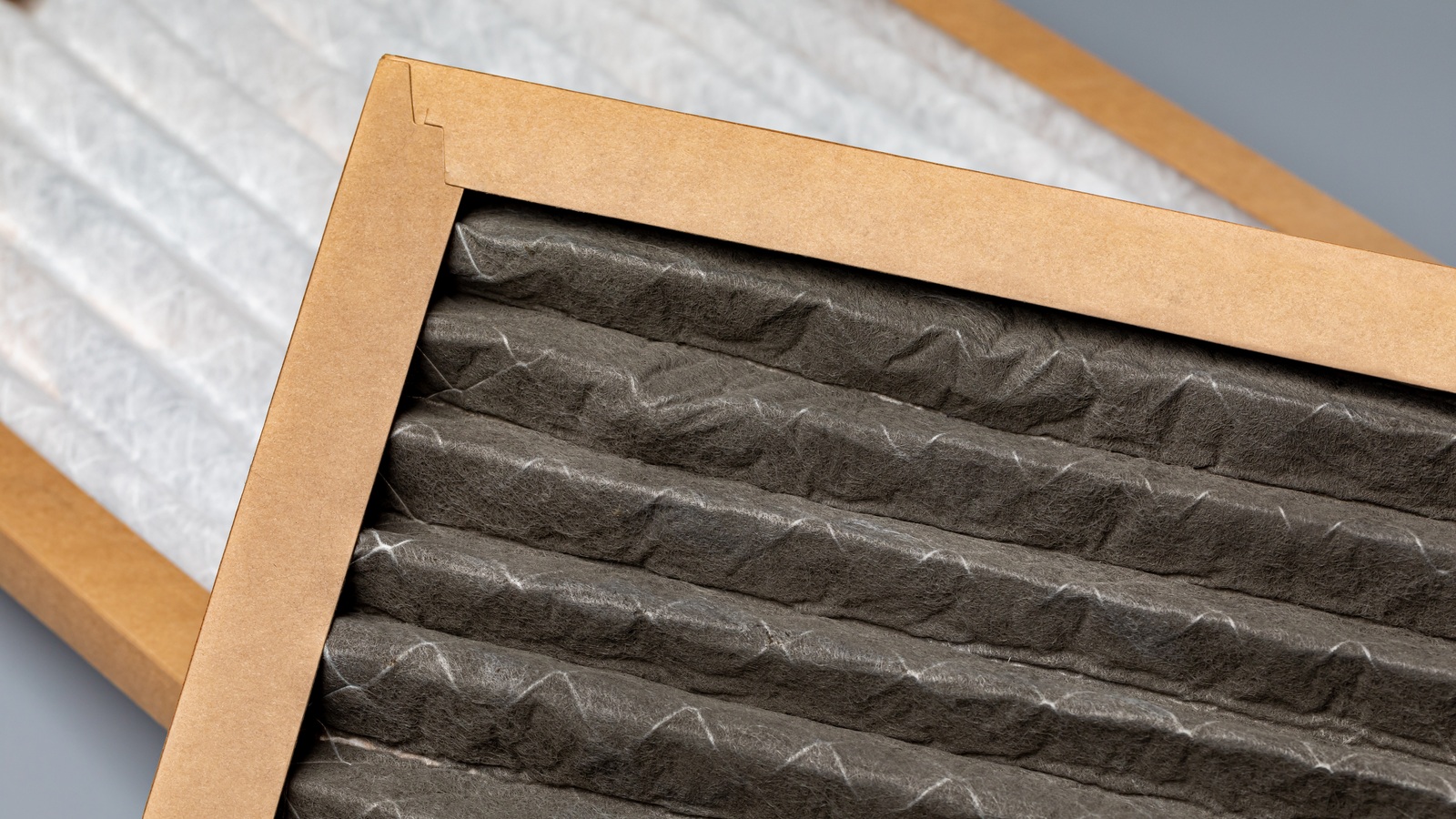 Clean white and dust-covered pleated furnace filters side by side