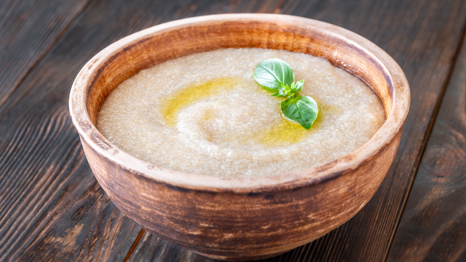 Bowl of soft cooked amaranth porridge with a small herb garnish