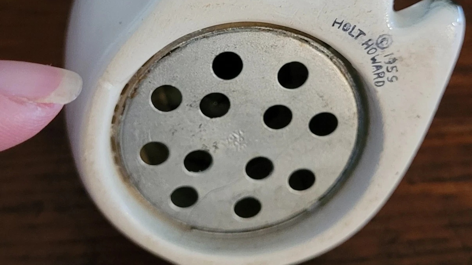 Circular perforated metal sound mechanism fitted into the underside of a Holt-Howard cat shaker.