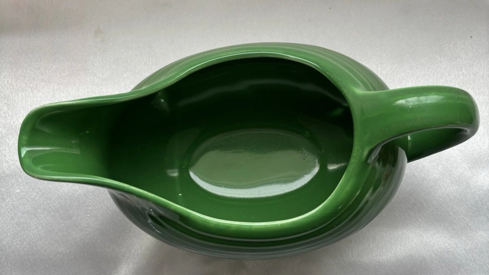 Top view of a vintage Medium Green Fiesta gravy boat showing its curved handle, pouring lip, and glossy interior.