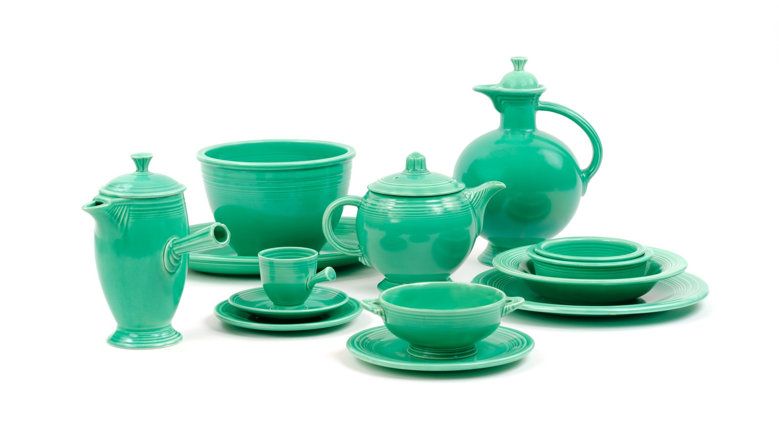 Collection of original Light Green Fiesta dinnerware, including a mixing bowl, teapot, plates, and coffee pieces.