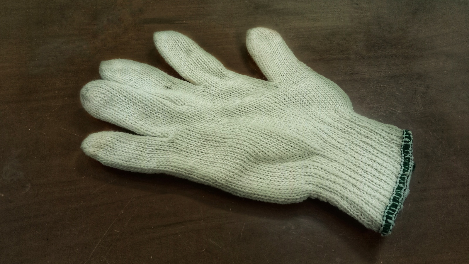 Uncoated knitted cotton gloves resting on a wooden surface