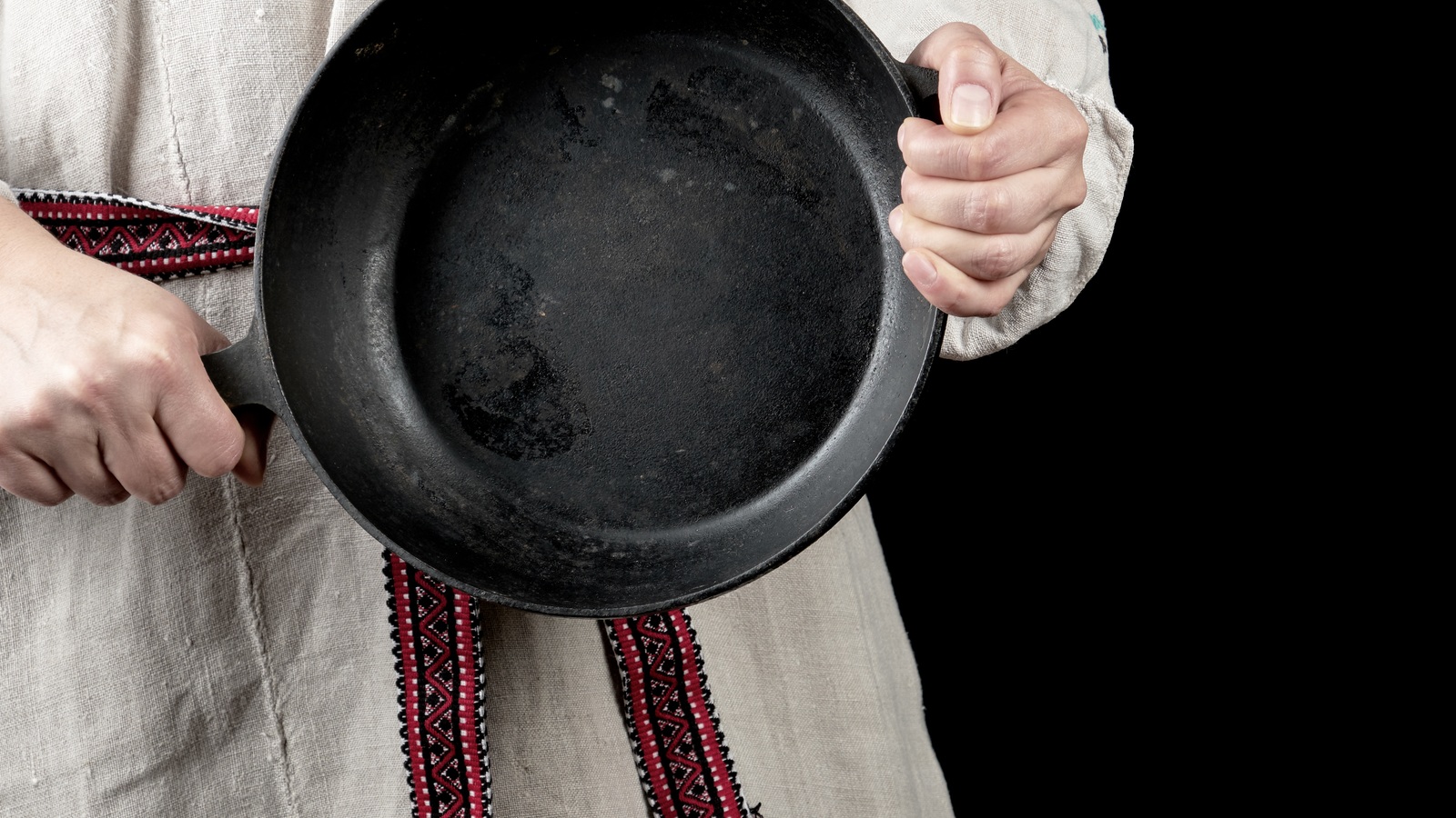 A woman holding a cast-iron pan by its handles