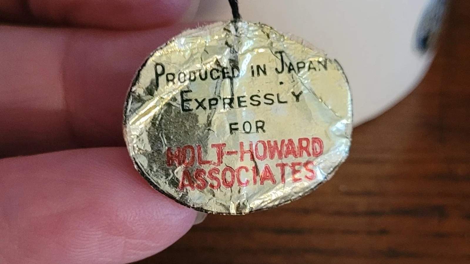 Original worn gold label reading Produced in Japan Expressly for Holt-Howard Associates, held beside a ceramic cat.