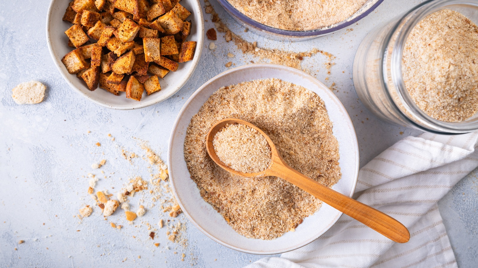 Homemade breadcrumbs in a bowl and jar with toasted bread cubes