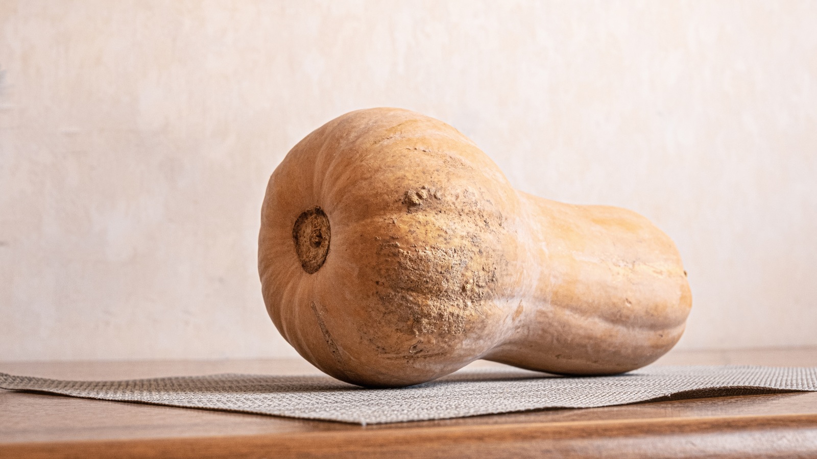 An intact whole butternut squash resting on an open tabletop