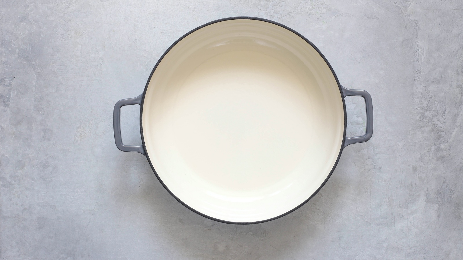 The pale enamel interior of an empty cast-iron pot