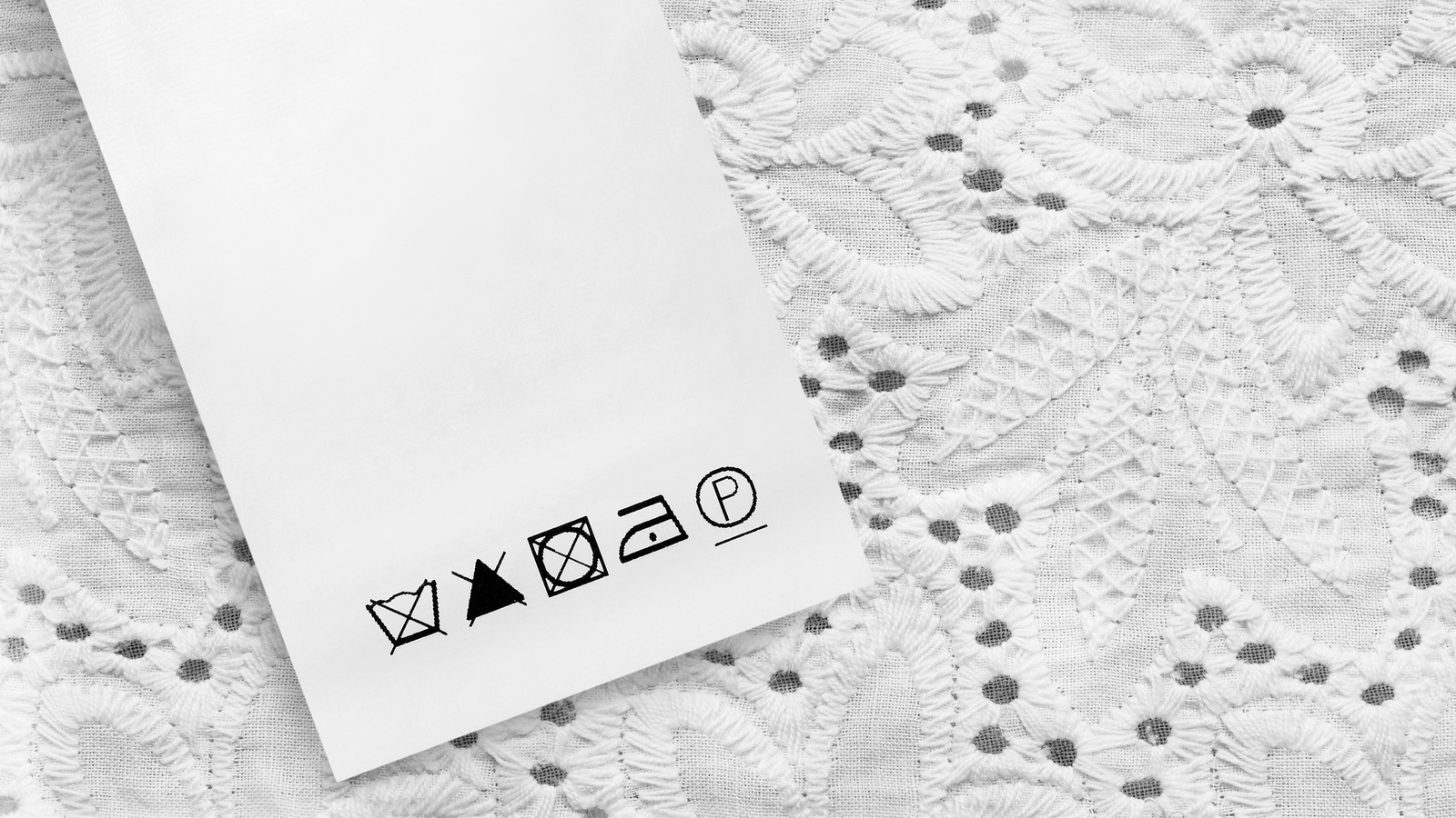 Fabric care label with washing and bleaching restrictions on white embroidered cloth