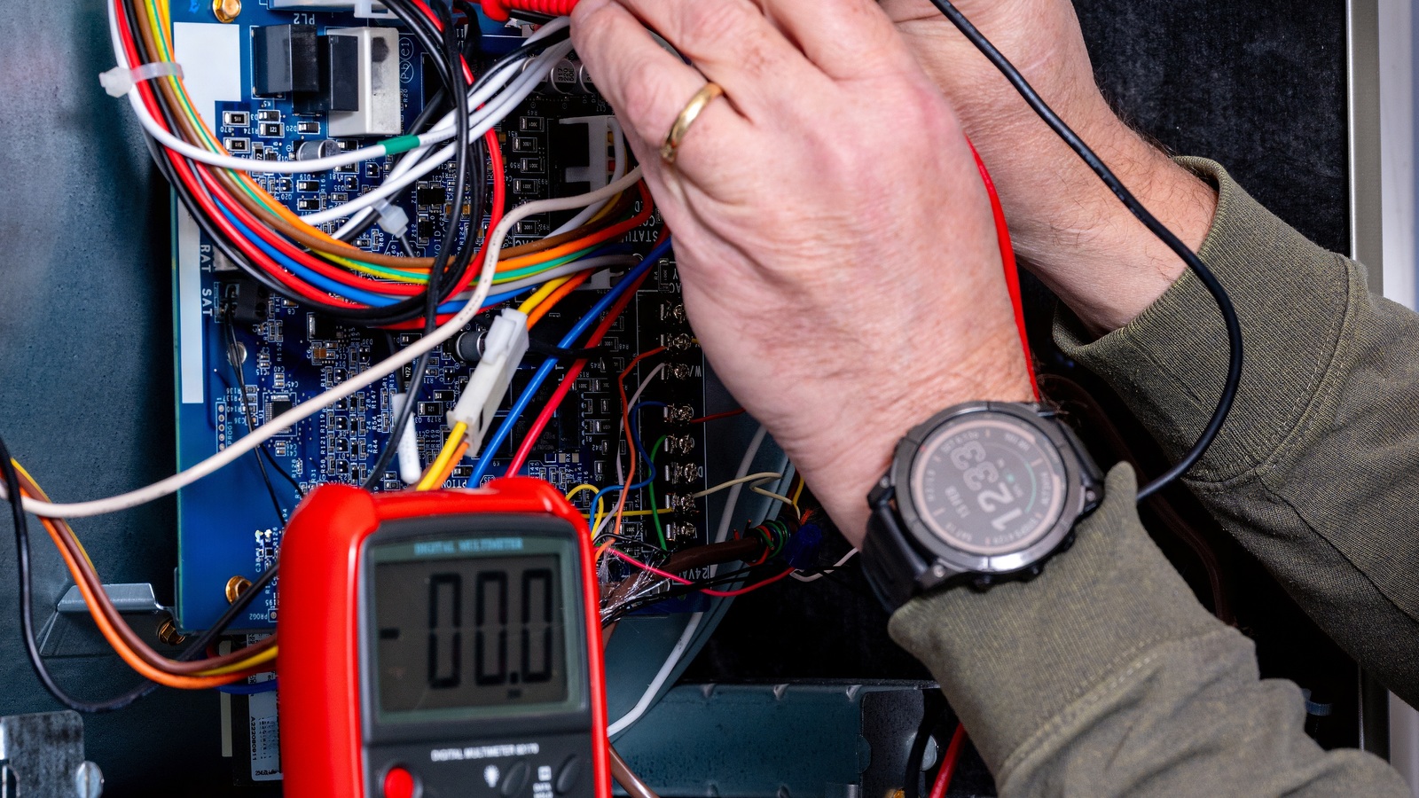 Technician using electrical test probes and a meter inside a furnace