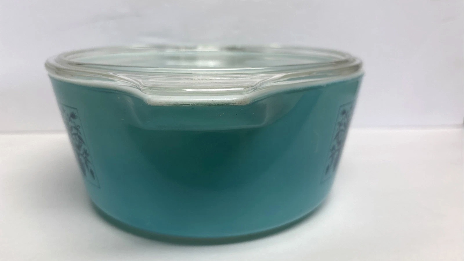 Side view of the blue Saxony Pyrex finish and dark blue pattern beneath its clear glass lid