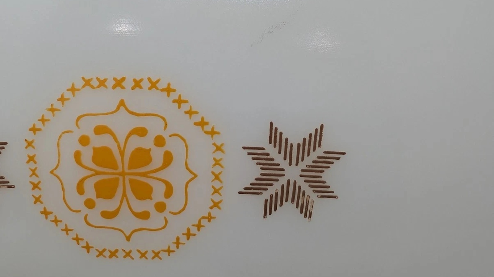 Close view of orange cross-stitch motifs and a brown eight-pointed star on Town and Country Pyrex