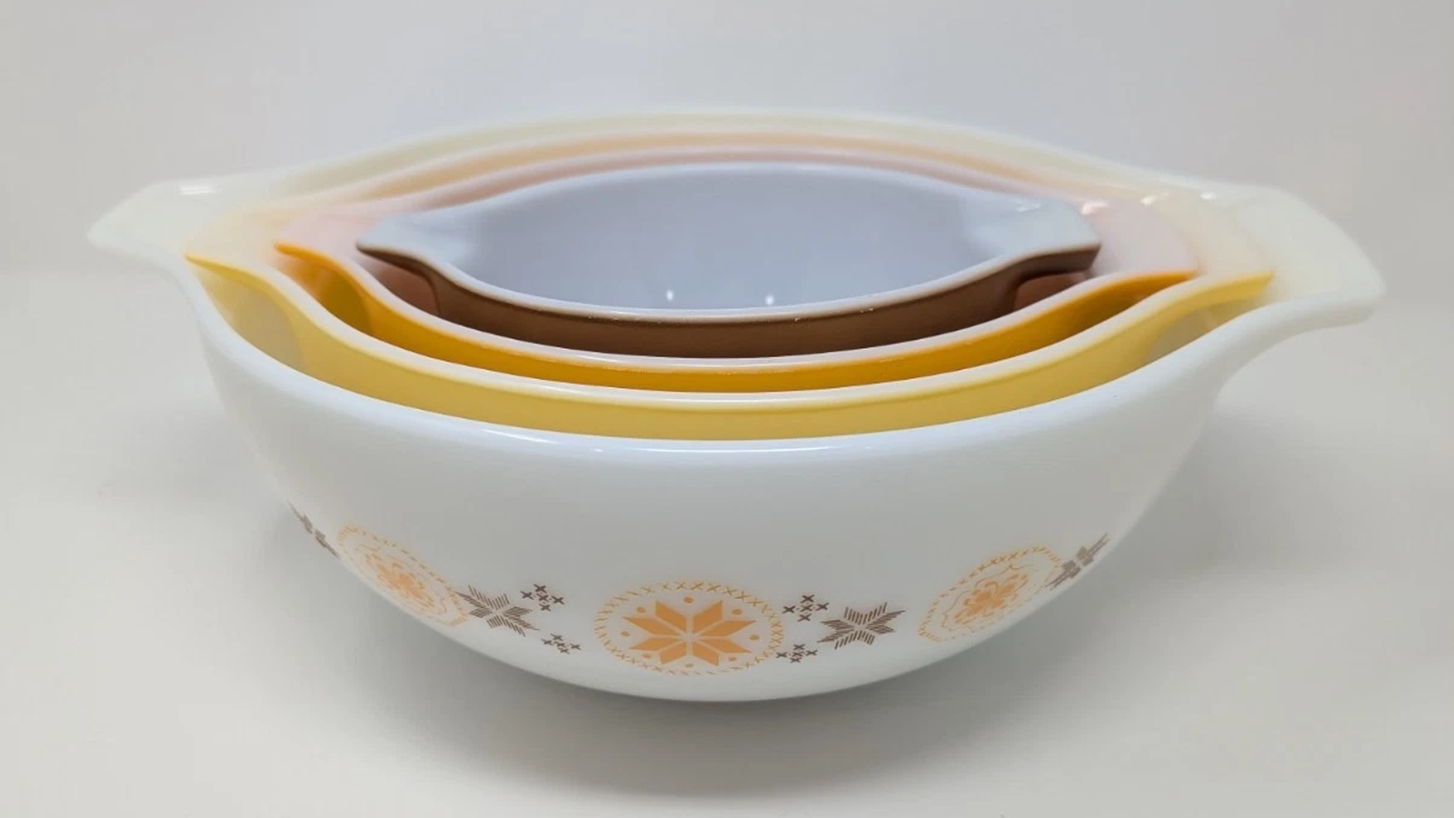 Town and Country Cinderella bowls nested together with brown, orange, yellow, and patterned white exteriors