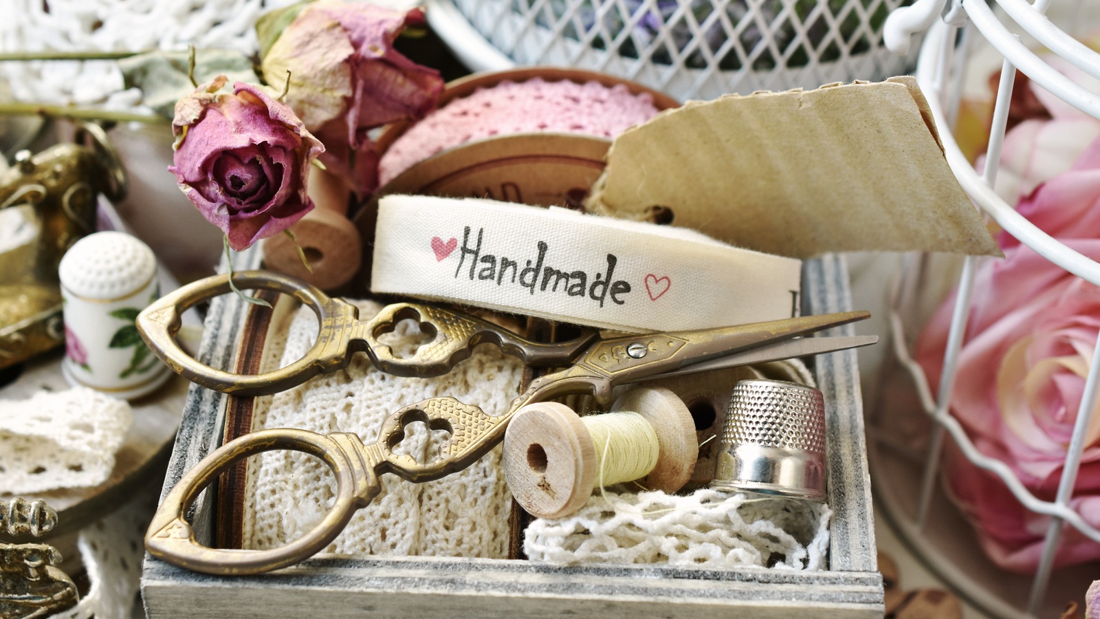 Vintage scissors, thread spools, lace and other sewing supplies kept in a wooden drawer