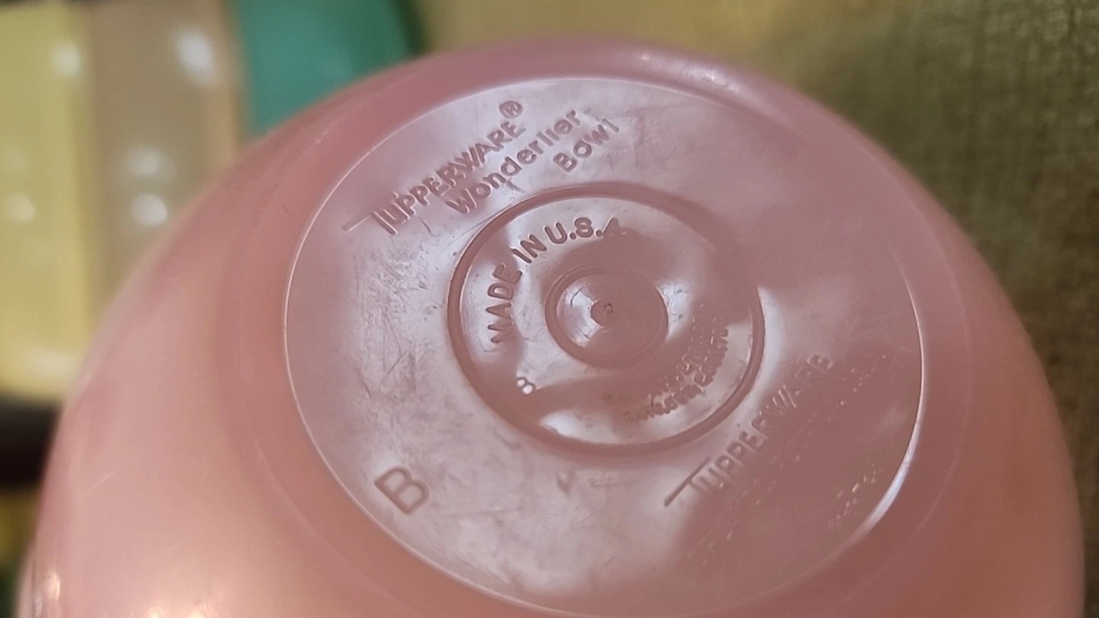 Embossed Tupperware Wonderlier Bowl and Made in U.S.A. markings on the base of a pink bowl.